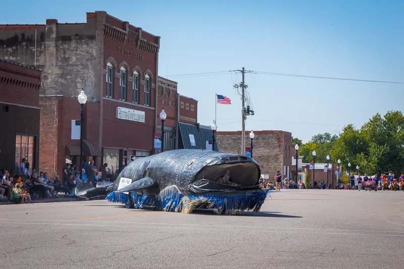 A giant whale float rolls down the parade route on a wave of blue fringe.
