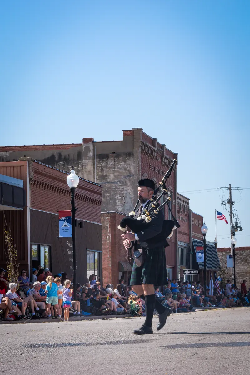 A bagpiper in Highland dress marches down Humboldt's main street.