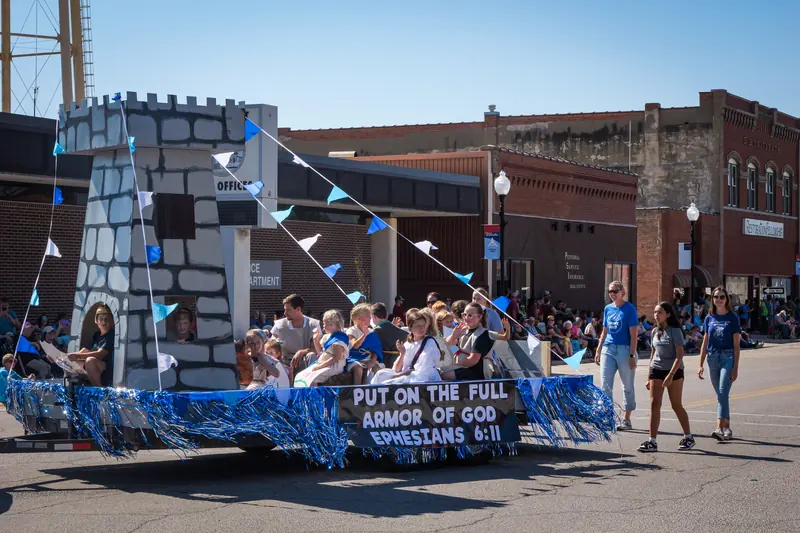 A stone-tower float carries a youth group, its skirt reading Put On the Full Armor of God, Ephesians 6:11.